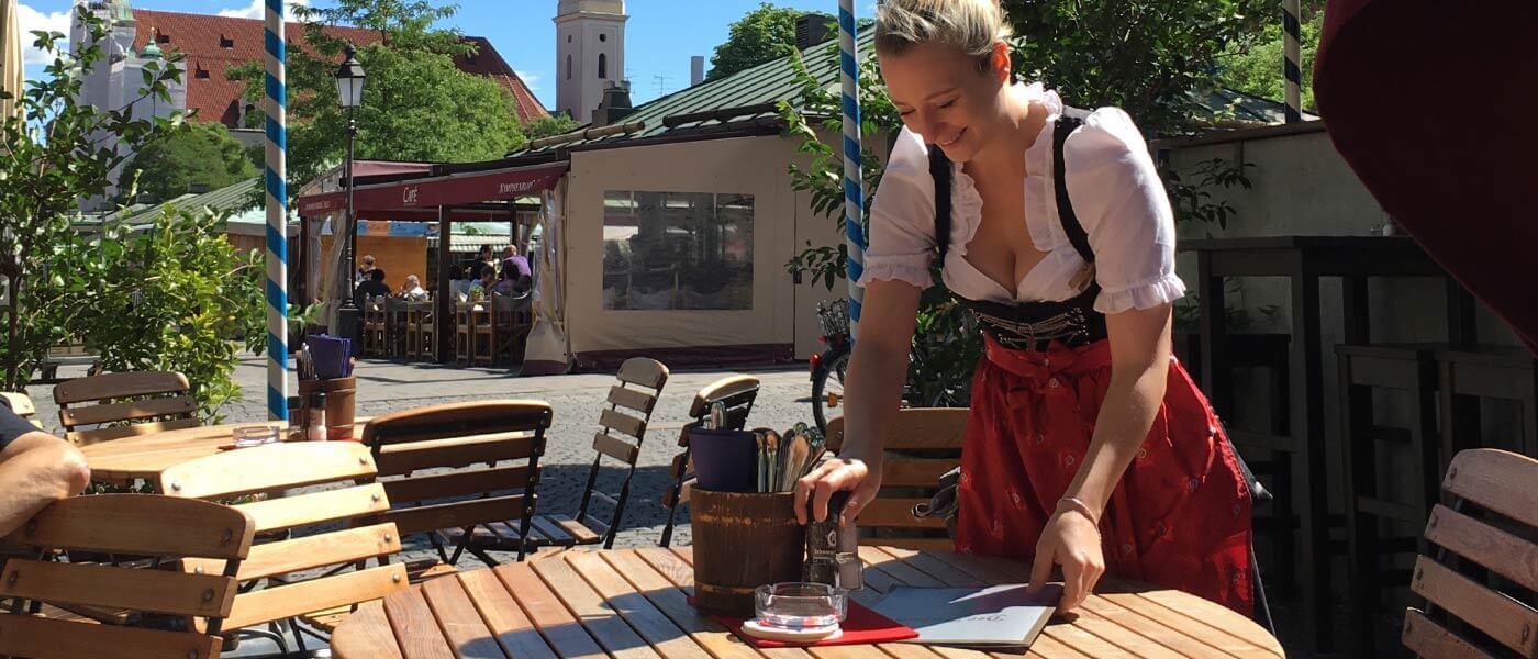 Die Biergartentische werden eingedeckt. Dahinter die ersten Zelte vom Viktualienmarkt in München